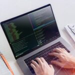 Hands typing code on laptop